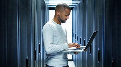 Man using a laptop in a hall of cabinets