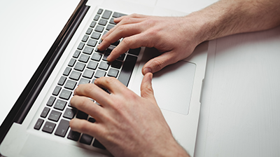 Hands typing on a laptop keyboard