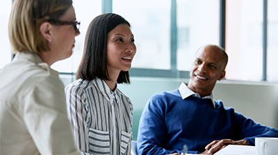 Two women and a man speaking during a meeting