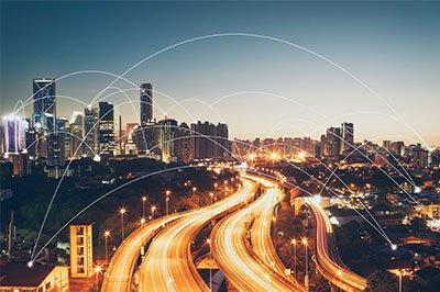 Multi lane highway at night with light trails and points throughout the city connected to each other