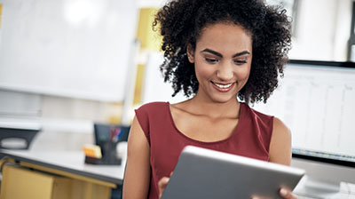 A woman smiling while using a tablet