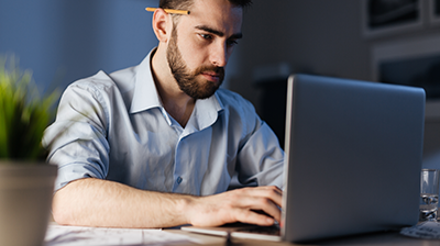 A bearded man working on a laptop