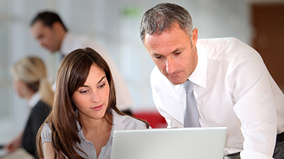 Man and woman in business attire looking at laptop together